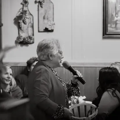 Black-and-white photo of Anna Munson speaking into a microphone at a community event